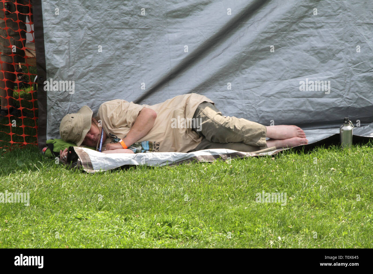 A concert goer is shown taking a quick nap during an outdoor music festival event. Stock Photo