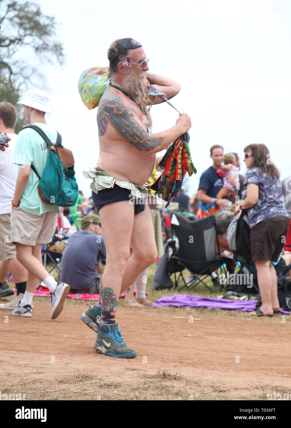 This concert goer shows off his tattoos, dollar bills and more, as he struts his stuff at an outdoor summer music festival. Stock Photo