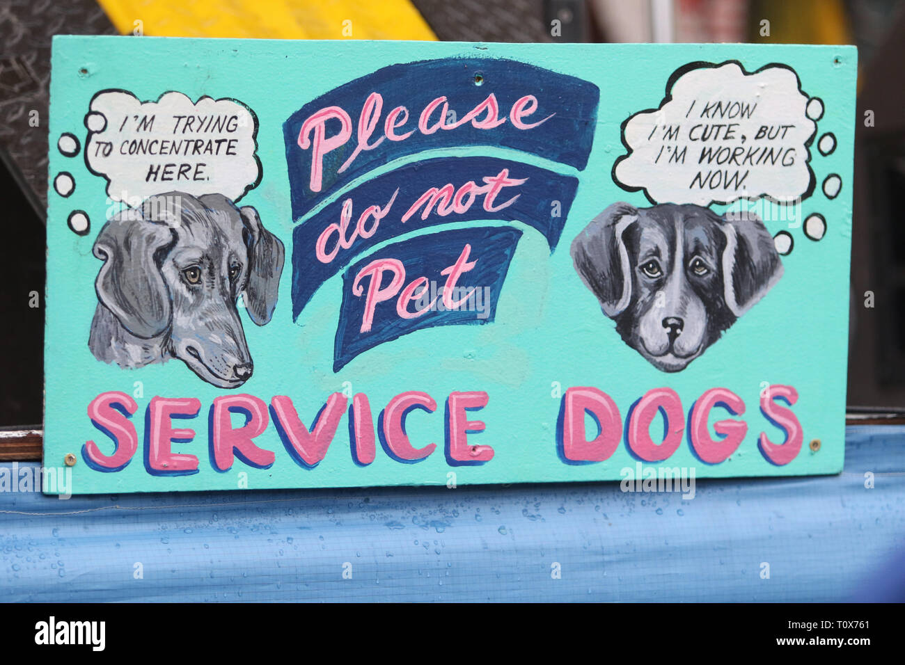 'Please Do Not Pet the Service Dogs' sign is shown on display at an outdoor music festival. Stock Photo