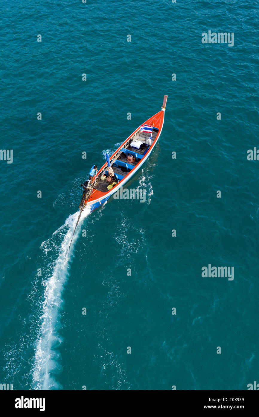 View from above, aerial view of a beautiful long tail boat that sails on a blue sea leaving behind a long wake of water. Phuket, Thailand. Stock Photo