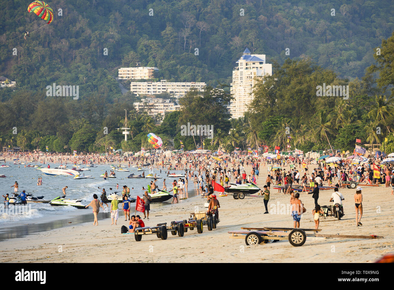 Patong beach crowded with tourists while some people do parasailing in
