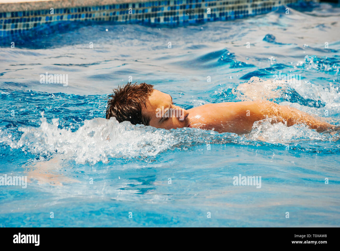 Young man swimmer train swimming in swimming pool. Recreation outdoor