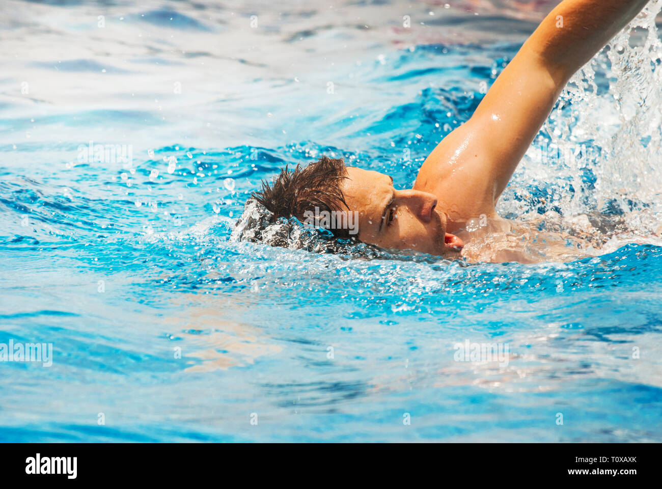 Young man swimmer train swimming in swimming pool. Recreation outdoor