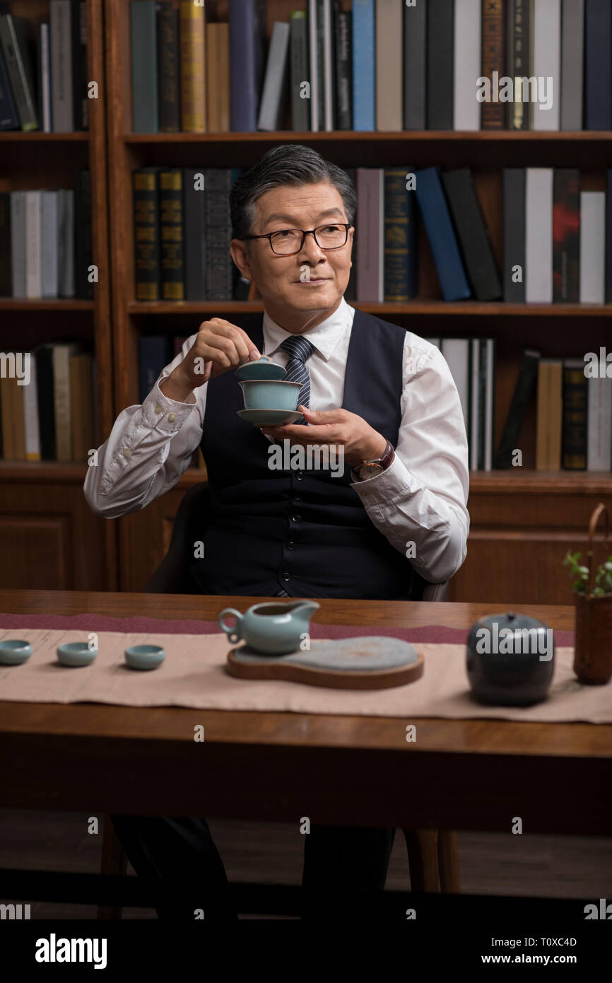 Senior businessman drinking tea in study Stock Photo
