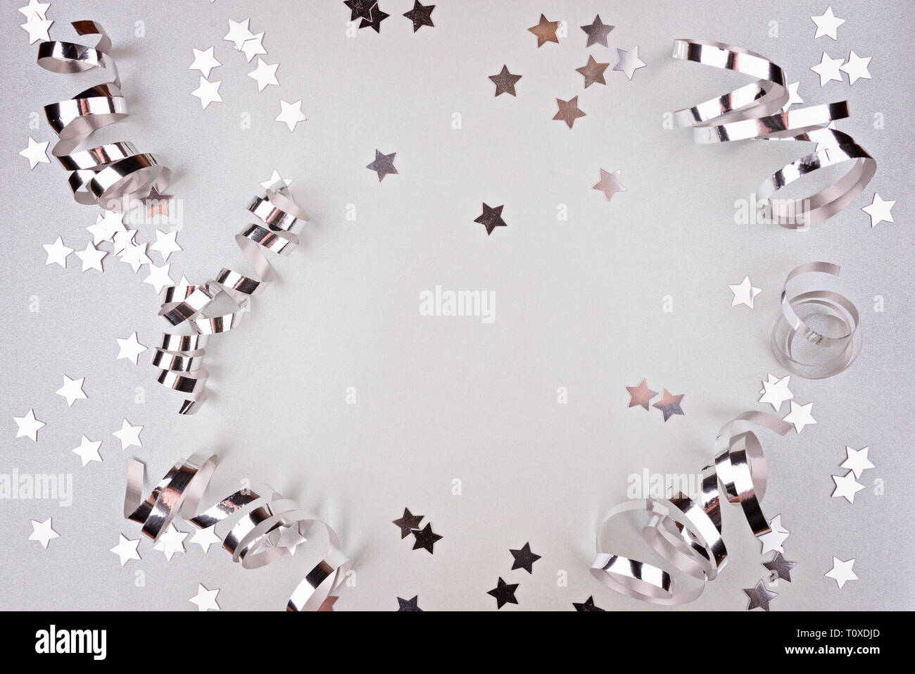 Background about a party, confetti, stars and streamers. Made in silver shades. Copy space. Top view Stock Photo