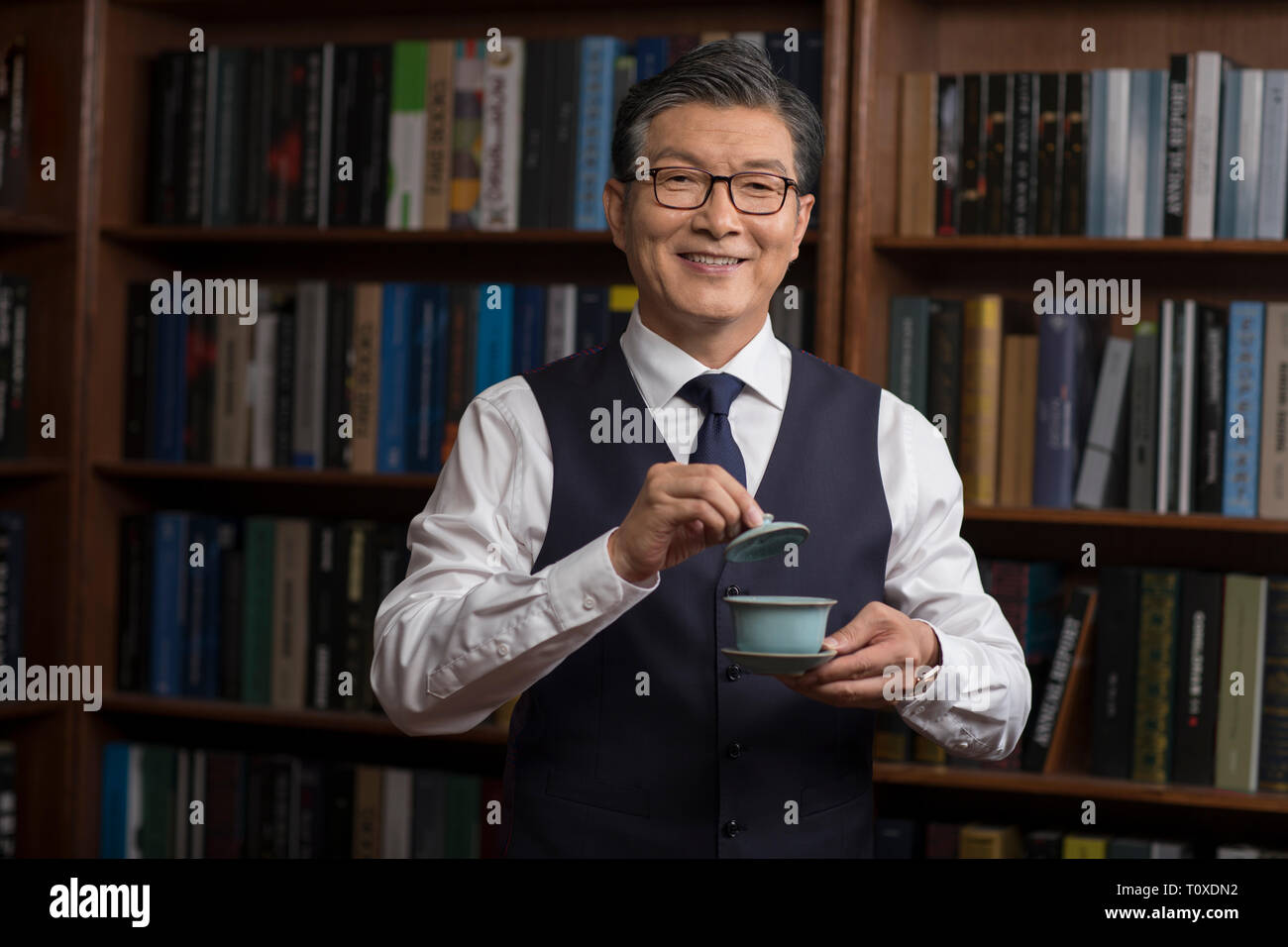 Senior businessman drinking tea in study Stock Photo