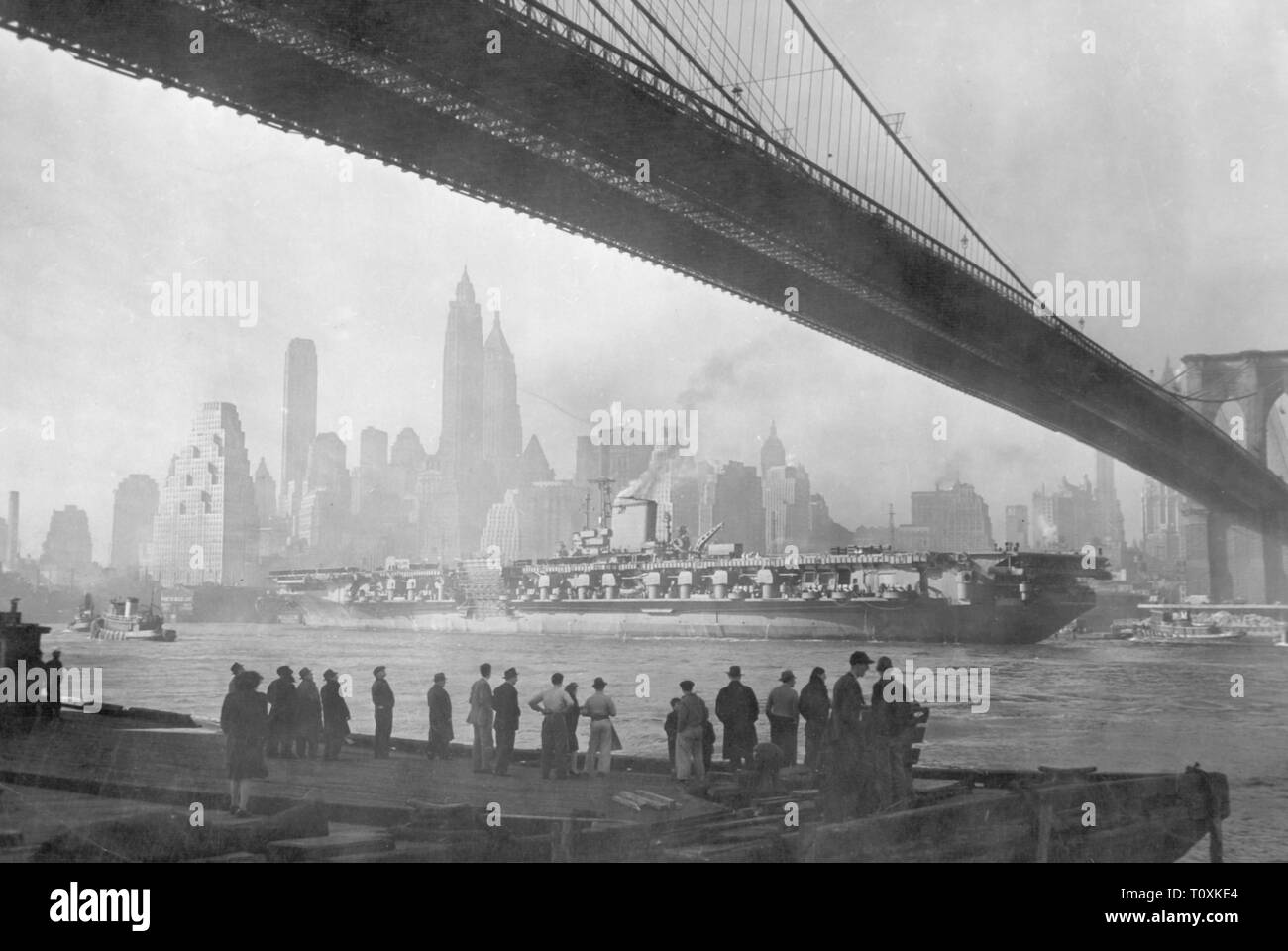 transport / transportation, navigation, warship, aircraft carrier USS 'Franklin D. Roosevelt', build in the Brooklyn Navy Yard, in commission 1945 - 1977, maiden voyage, East River, New York City, 27.10.1945, haze, mist, hazy, hazier, Brooklyn Bridge, river, rivers, bridge, bridges, skyline, cruise, people, US navy, American Navy, man-of-war, CV-42, military, naval forces, armed forces, USA, United States of America, 20th century, 1940s, transport, transportation, warship, warships, flattop, aircraft carriers, flattops, attack aircraft carrier, c, Additional-Rights-Clearance-Info-Not-Available Stock Photo