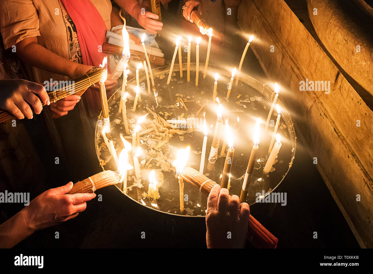 Close up of many hands burning candles after the Holy Fire miraculously appeared at Temple of the Lord's Coffin, Jerusalem, Israel. Pilgrims taking ho Stock Photo