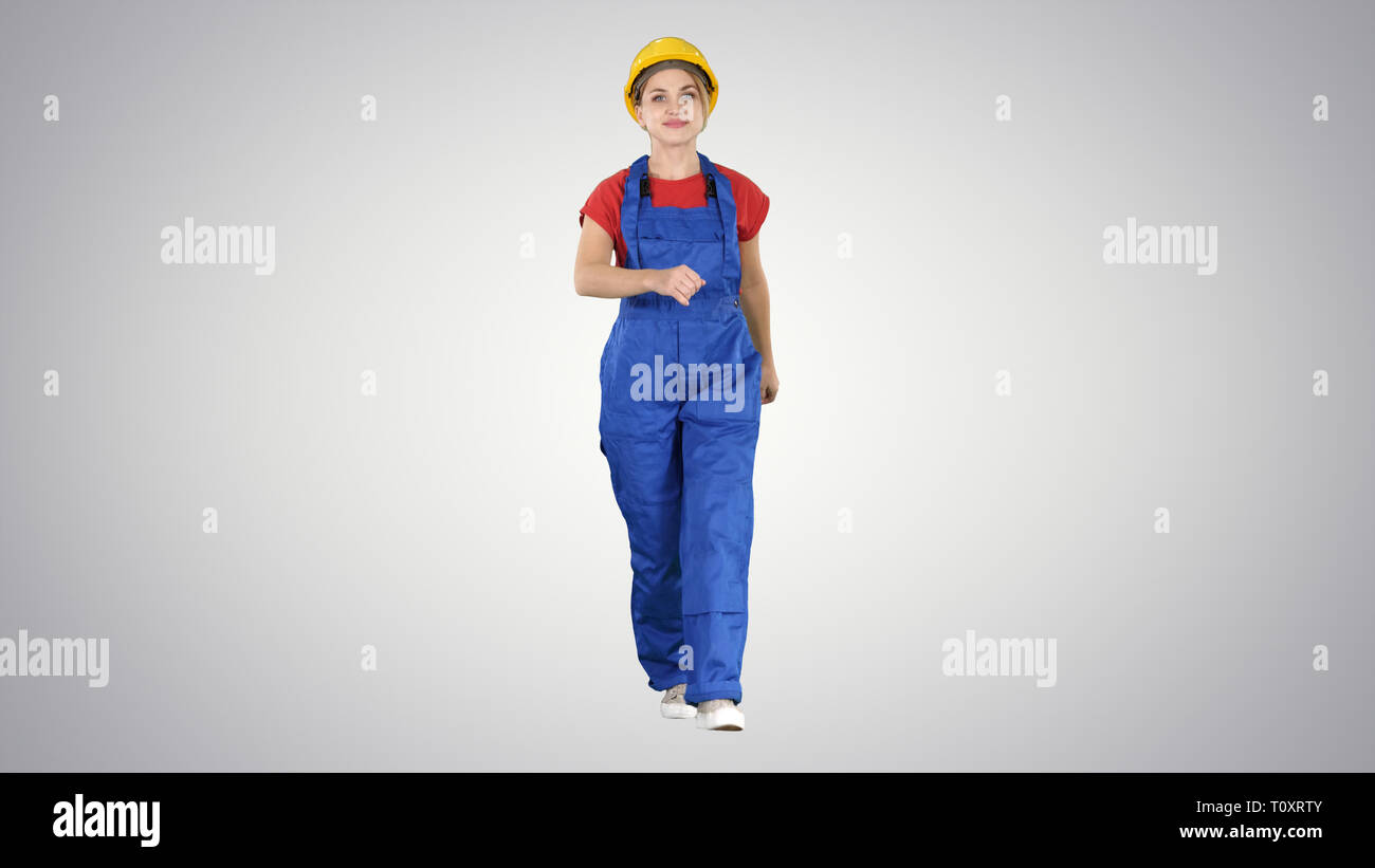 Confident experienced forewoman walking with will to work on gradient background. Stock Photo