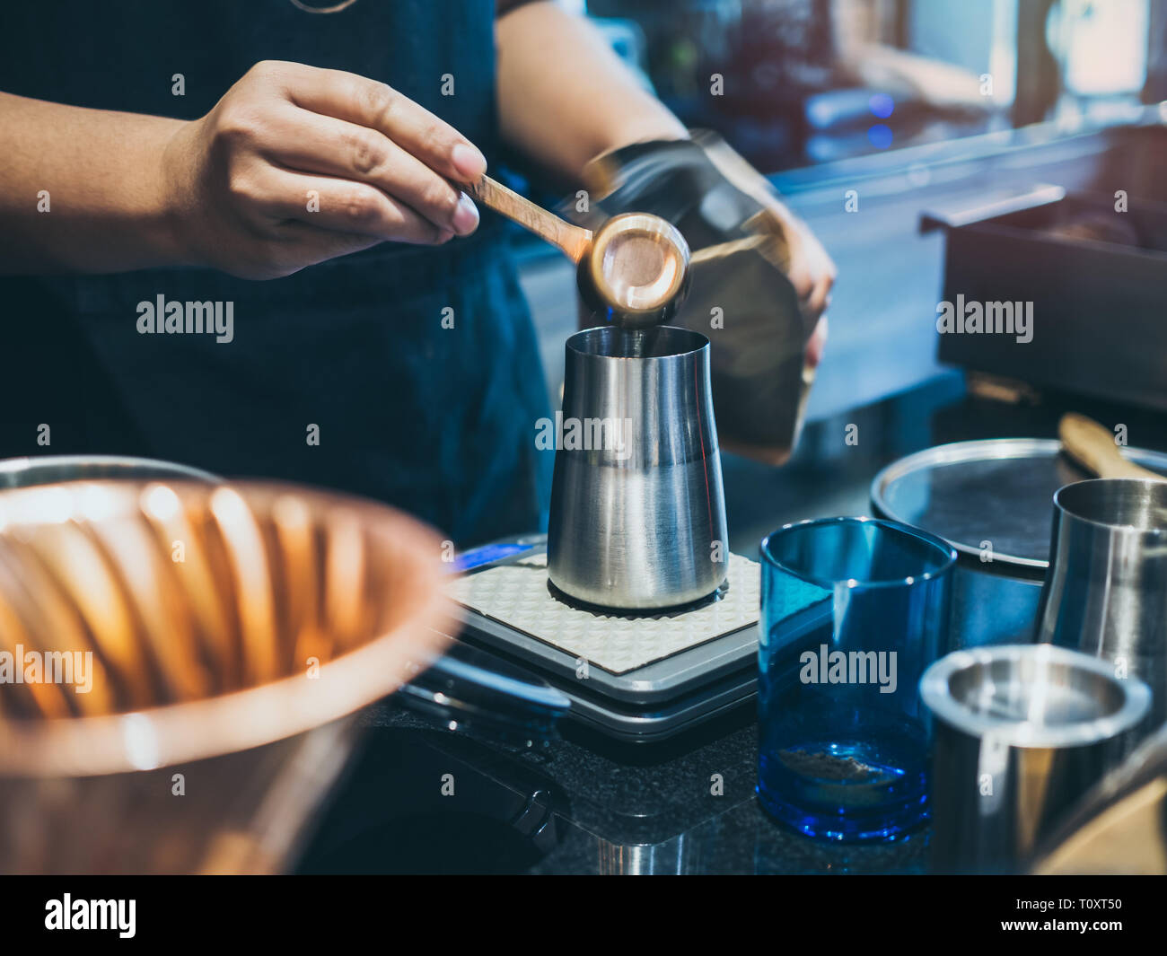 Barista's hand putting ground coffee in stainless steel manual coffee