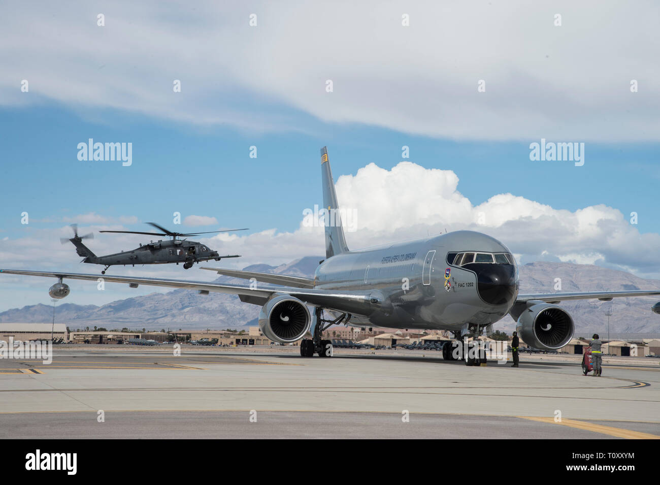 A Colombian 767 Multi-Mission Tanker Transport Jupiter aircraft starts its engine prior to flight while a U.S. Air Force HH-60 Pave Hawk flies behind during Red Flag 19-2 at Nellis Air Force Base, Nev., March 12, 2019. Red Flag is America’s premier integration air combat exercise focused on readiness, partnering and integrating expeditionary wing strike operations. (U.S. Air Force photo by Tech. Sgt. Angela Ruiz) Stock Photo