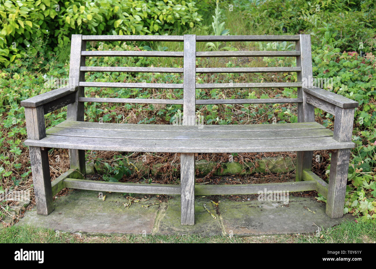 Traditional Curved Wooden Park Seat On Stone Paving Slabs