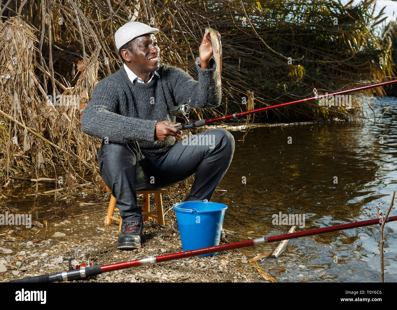 Portrait of African man fishing with rods on river and holding fish Stock  Photo - Alamy