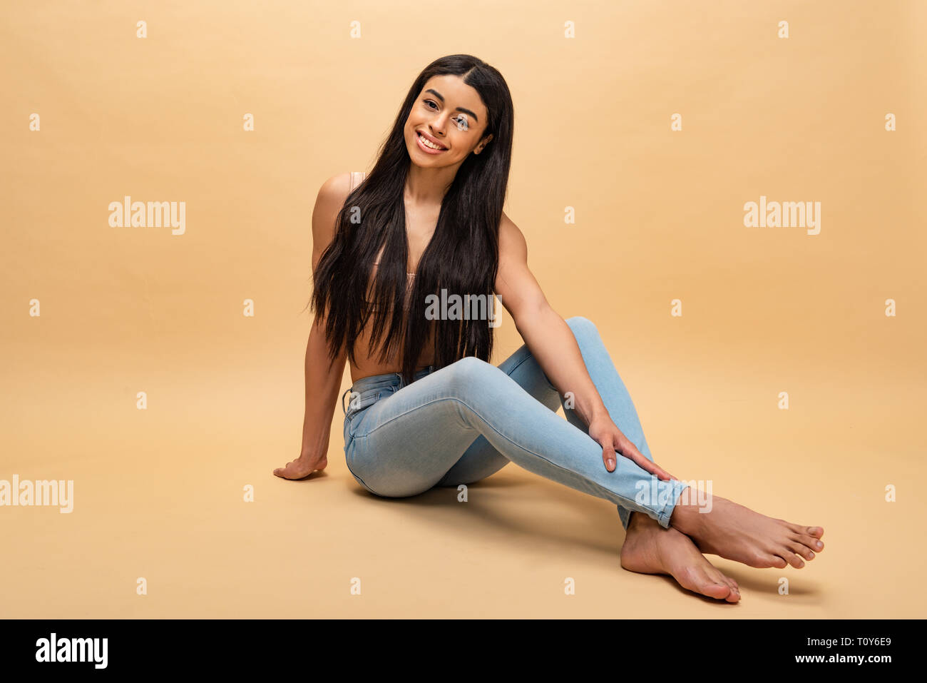 smiling african american woman sitting with crossed legs and looking at camera Stock Photo