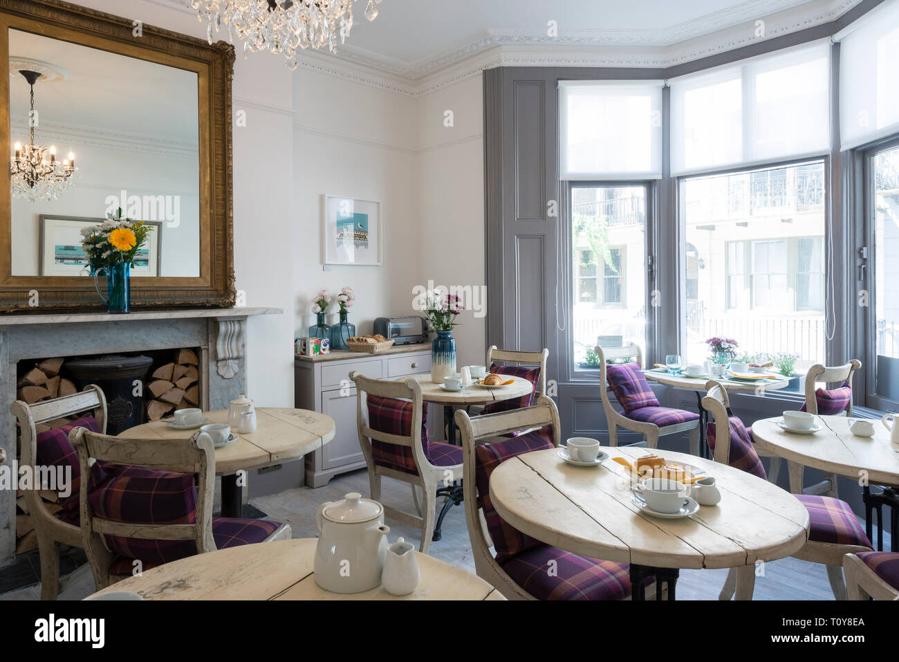 a dining room in a bed and breakfast hotel is laid out for breakfast Stock Photo