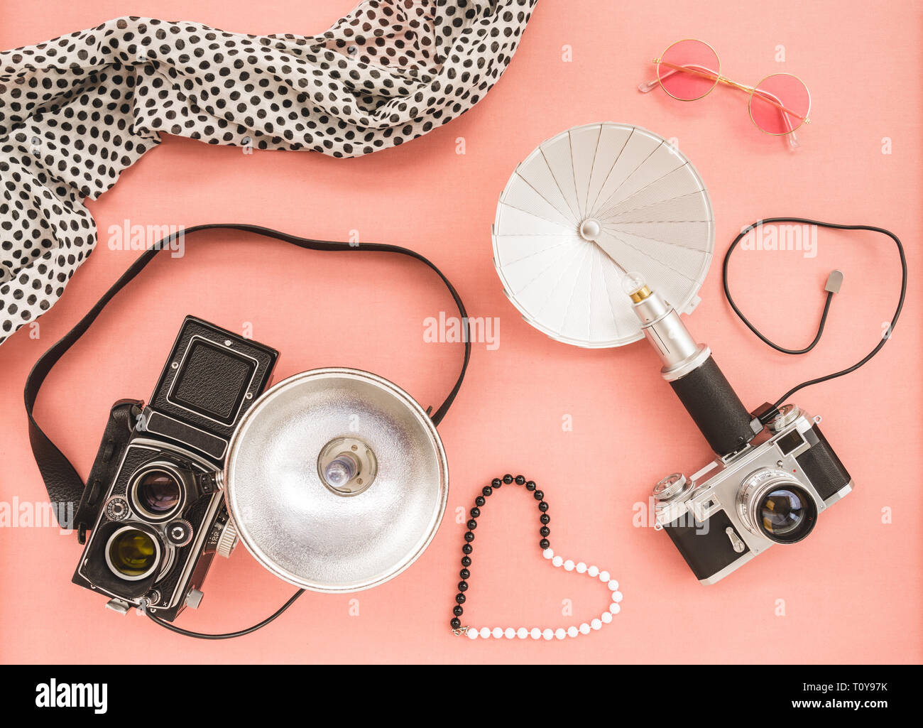 Vintage photo cameras with flashes, on pink canvas background. Stock Photo