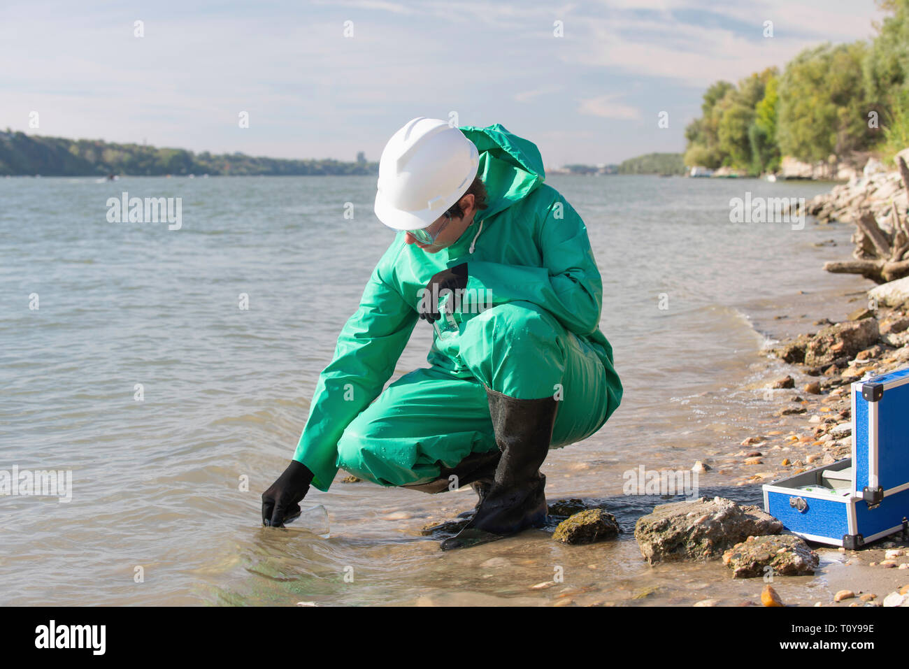 Water quality inspector filling up sample container with river water