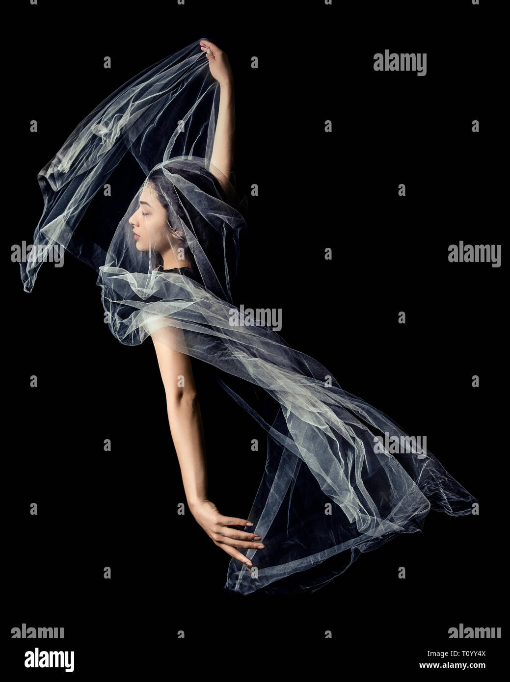 Young woman dancing with tulle against black background Stock Photo