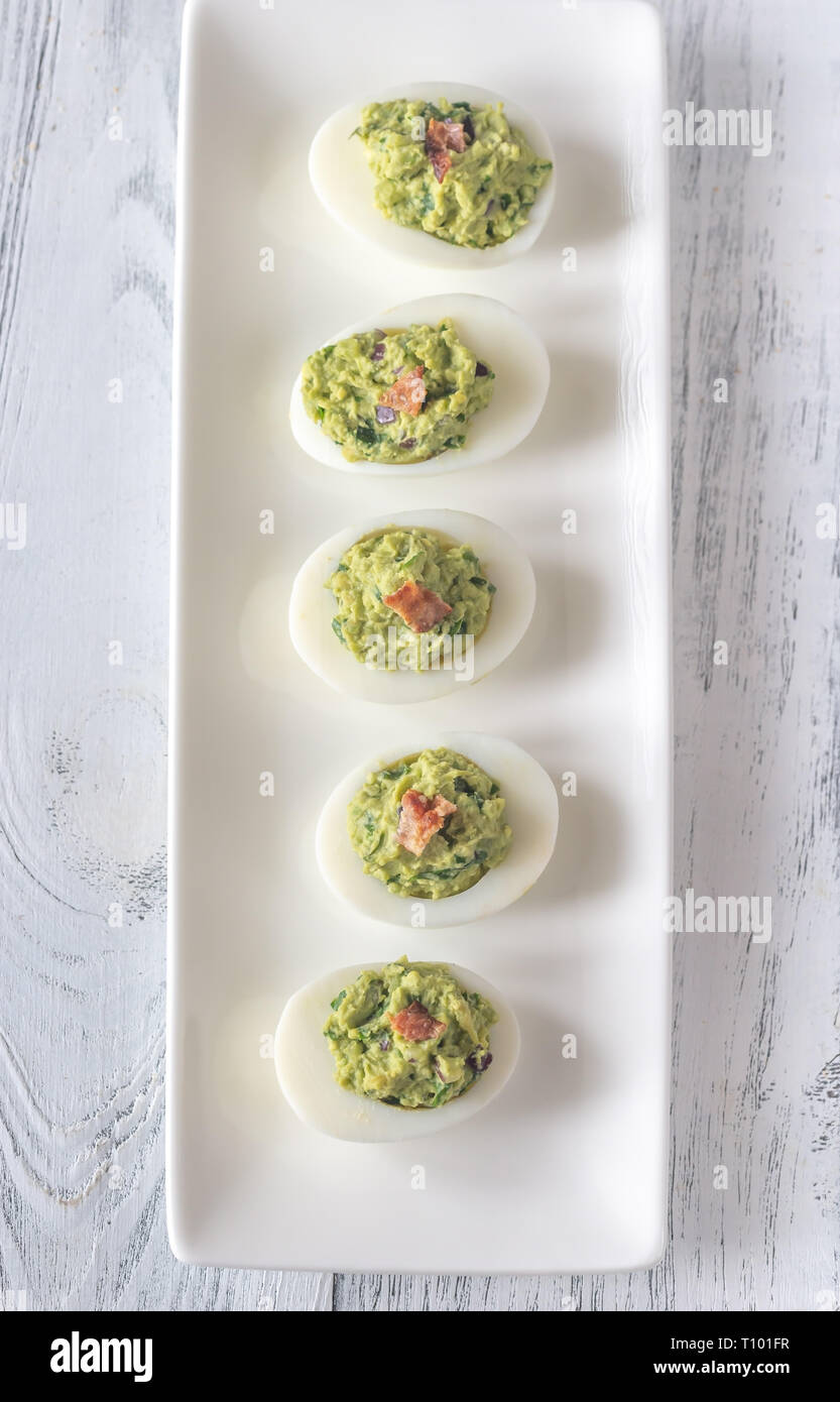 Guacamole and bacon deviled eggs on the white plate Stock Photo