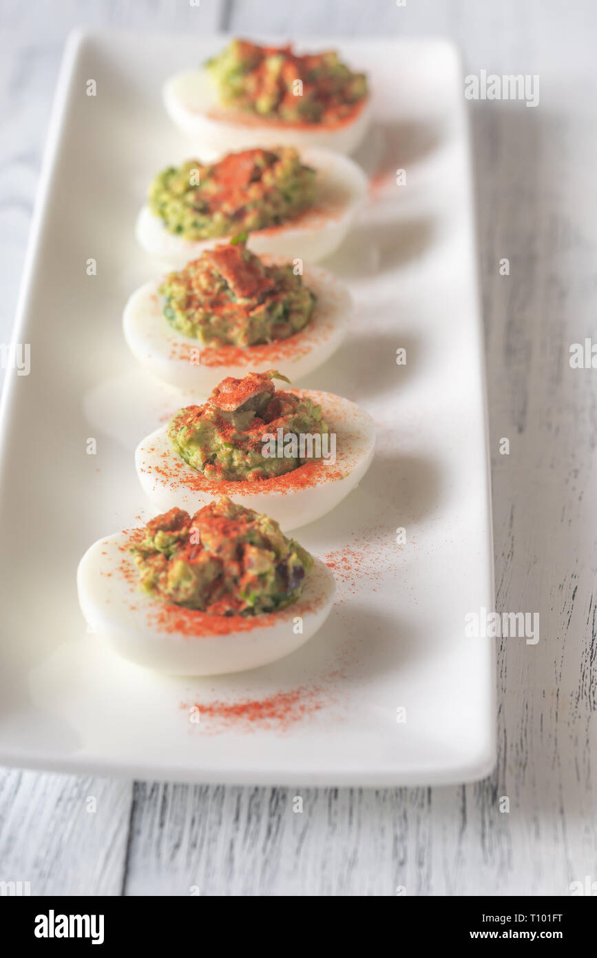 Guacamole and bacon deviled eggs on the white plate Stock Photo