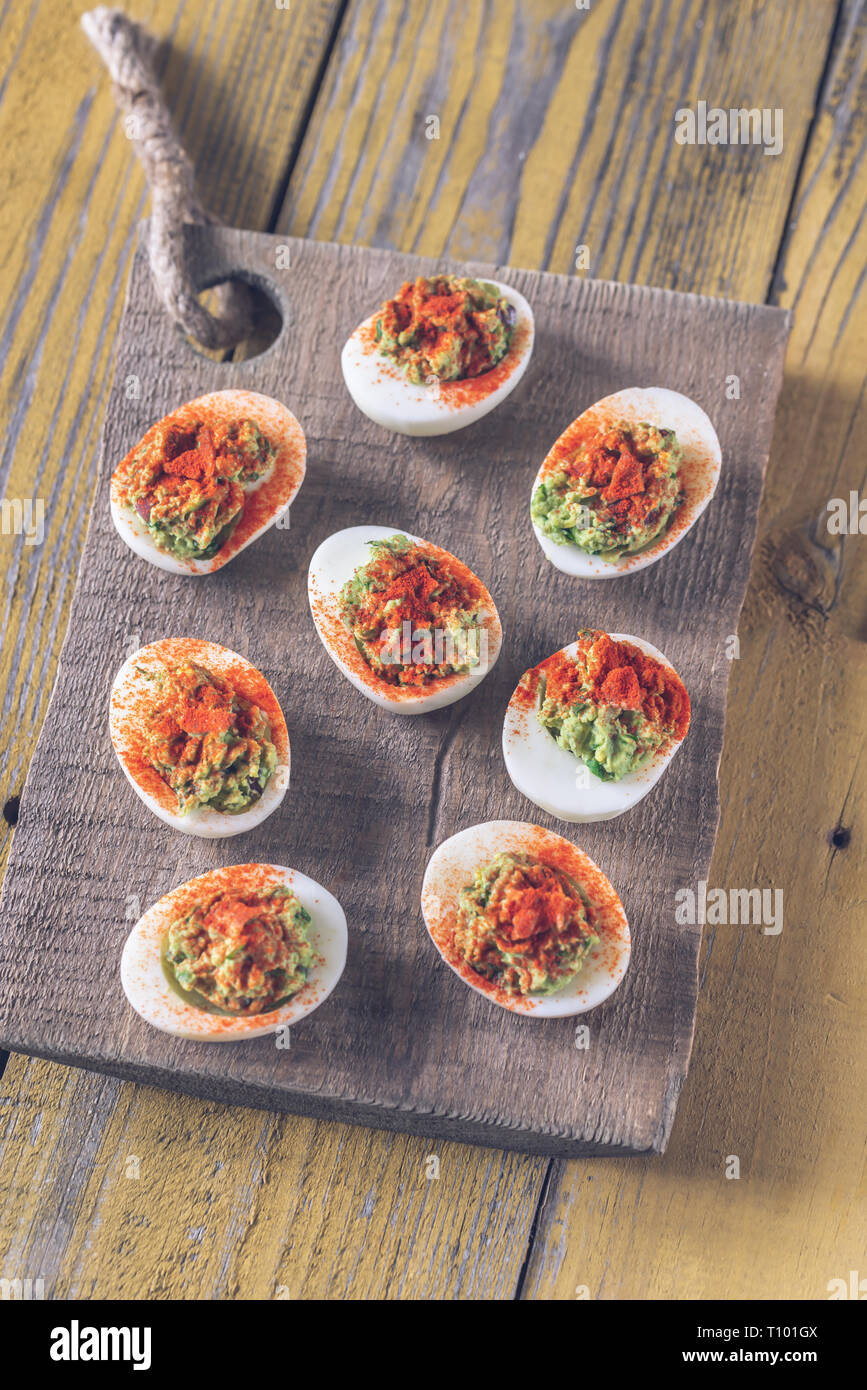 Guacamole and bacon deviled eggs on cutting board Stock Photo