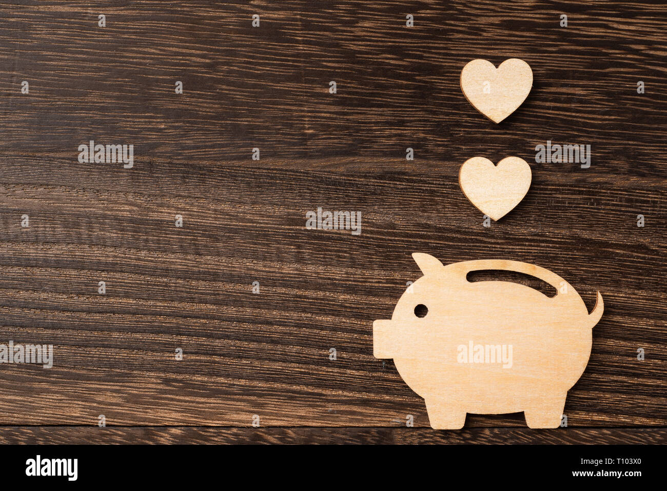 financial and design concept - wooden moneybox pig piece on dark wood background. it's saving, investing concept Stock Photo