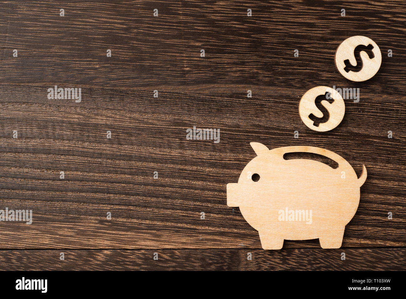 financial and design concept - wooden moneybox pig piece on dark wood background. it's saving, investing concept Stock Photo