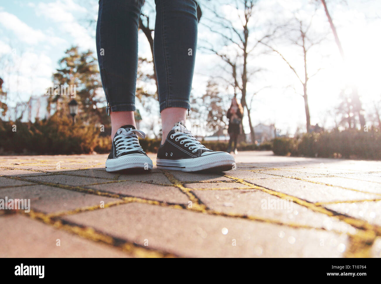 black sneakers on the legs of a woman walking in the park Stock Photo