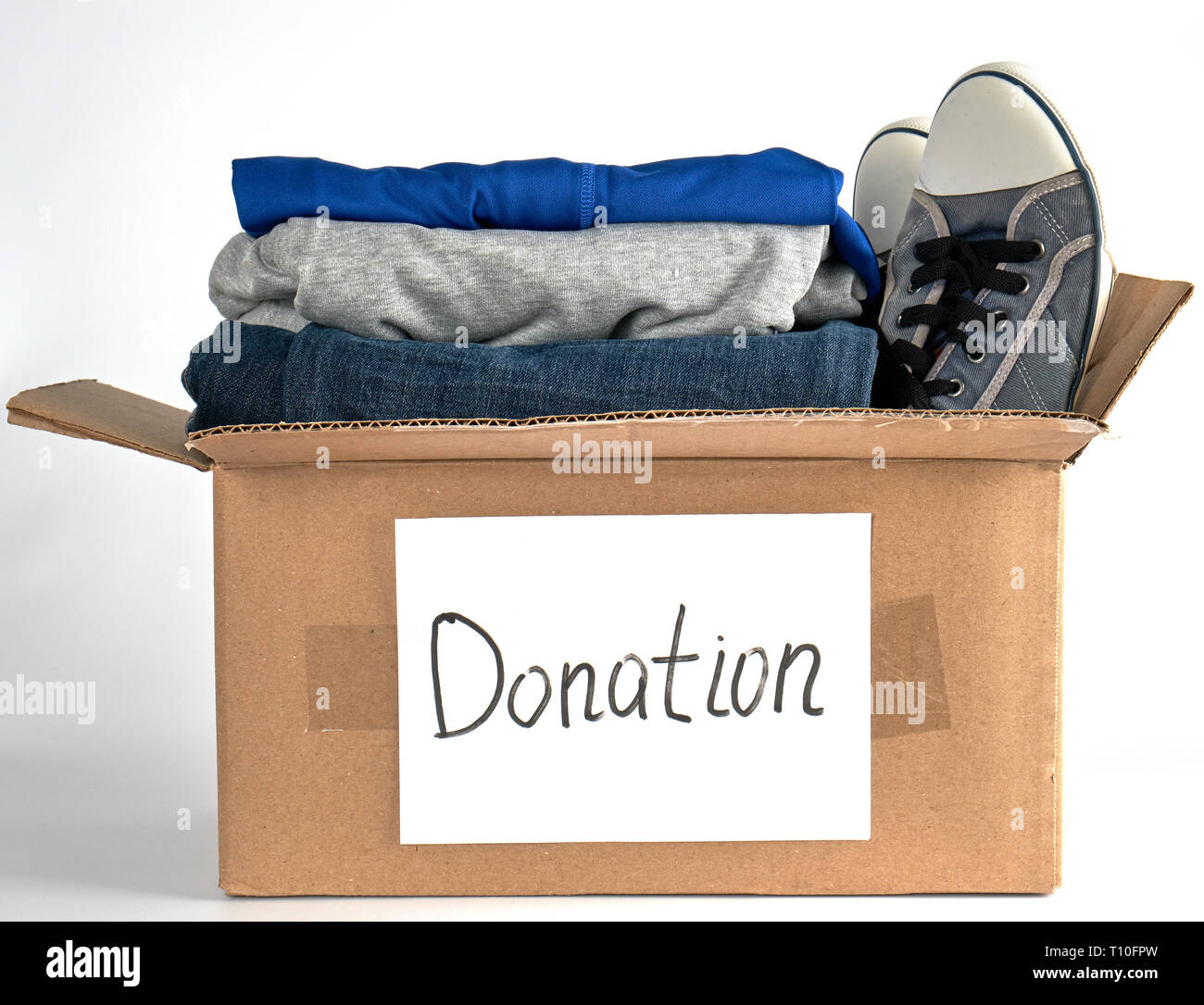 folded clothes in a brown paper box with the inscription donation  on a white background, the concept of helping people in need Stock Photo