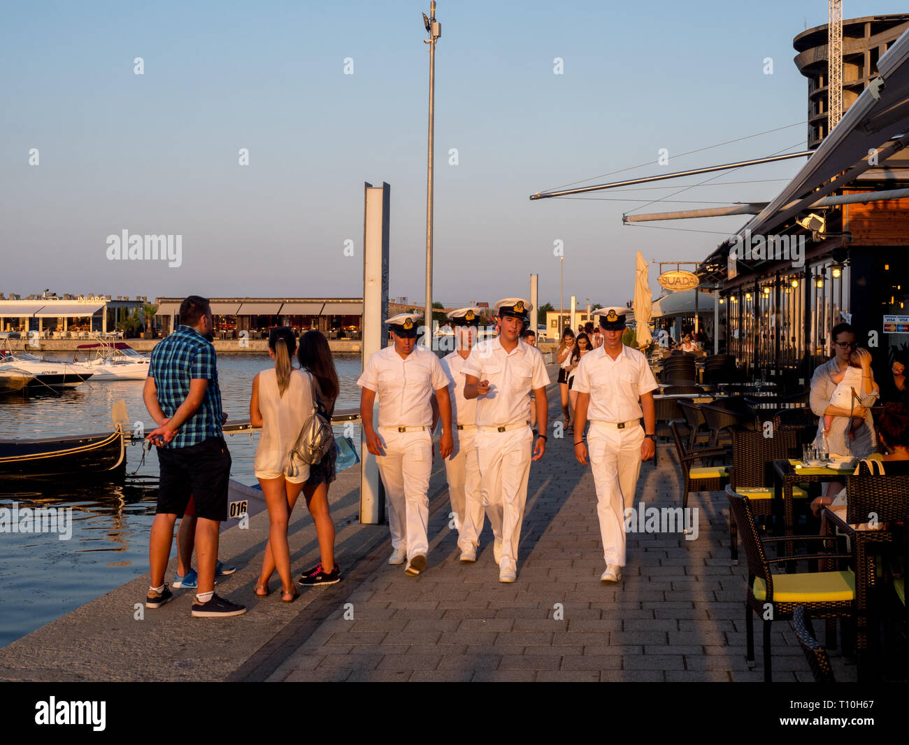 Sailors walking past restaurants located around Constanta marina. Stock Photo