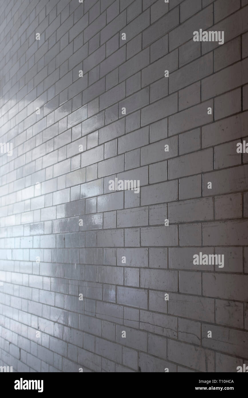 Ghostly shadow of person reflected in white glazed brick wall. Stock Photo