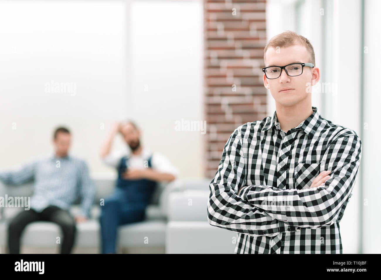 serious young man standing in spacious office Stock Photo