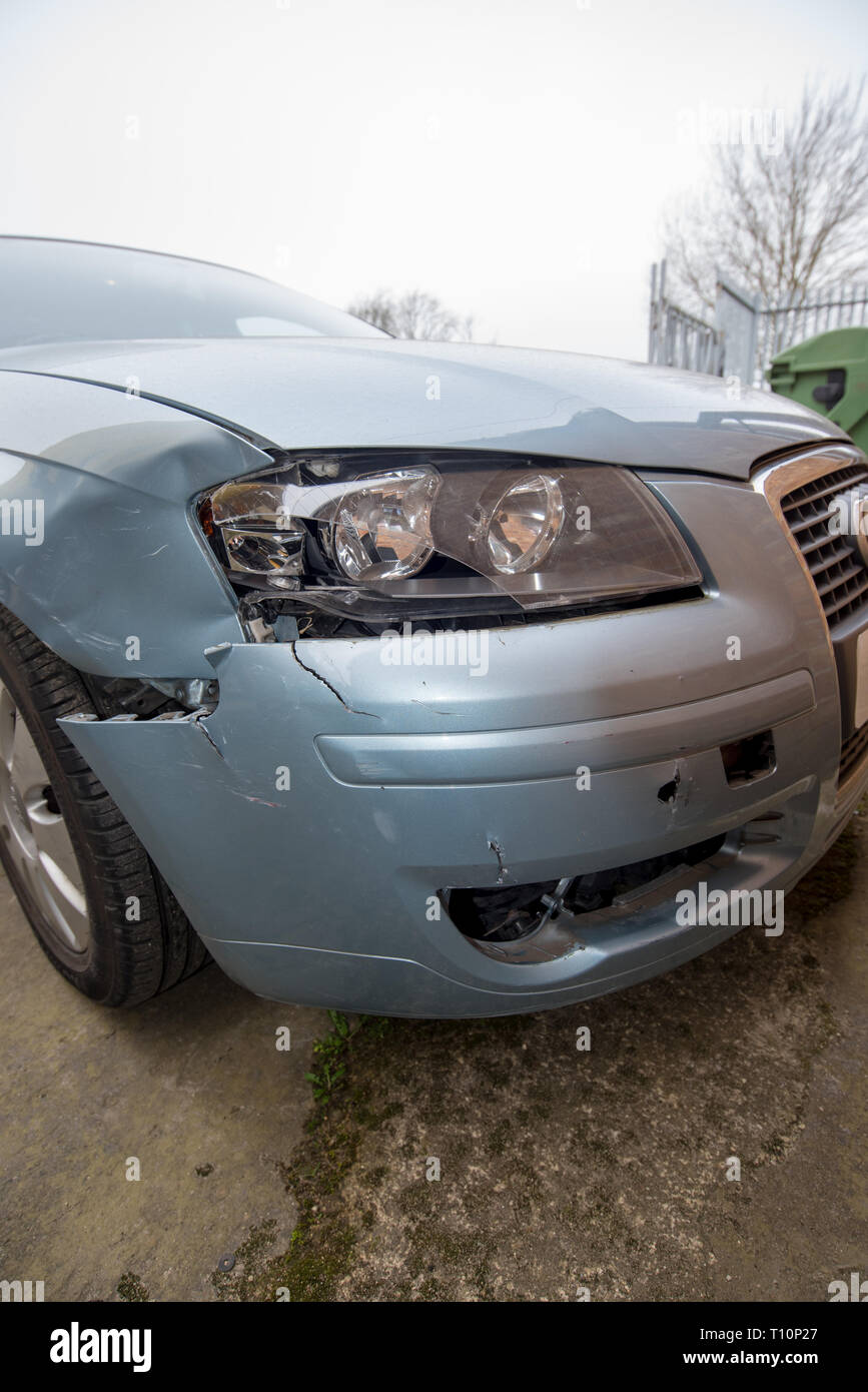 Car crash. Silver vehicle in front end collision. Damage to bumper/ wheel arch/ headlight. Brick