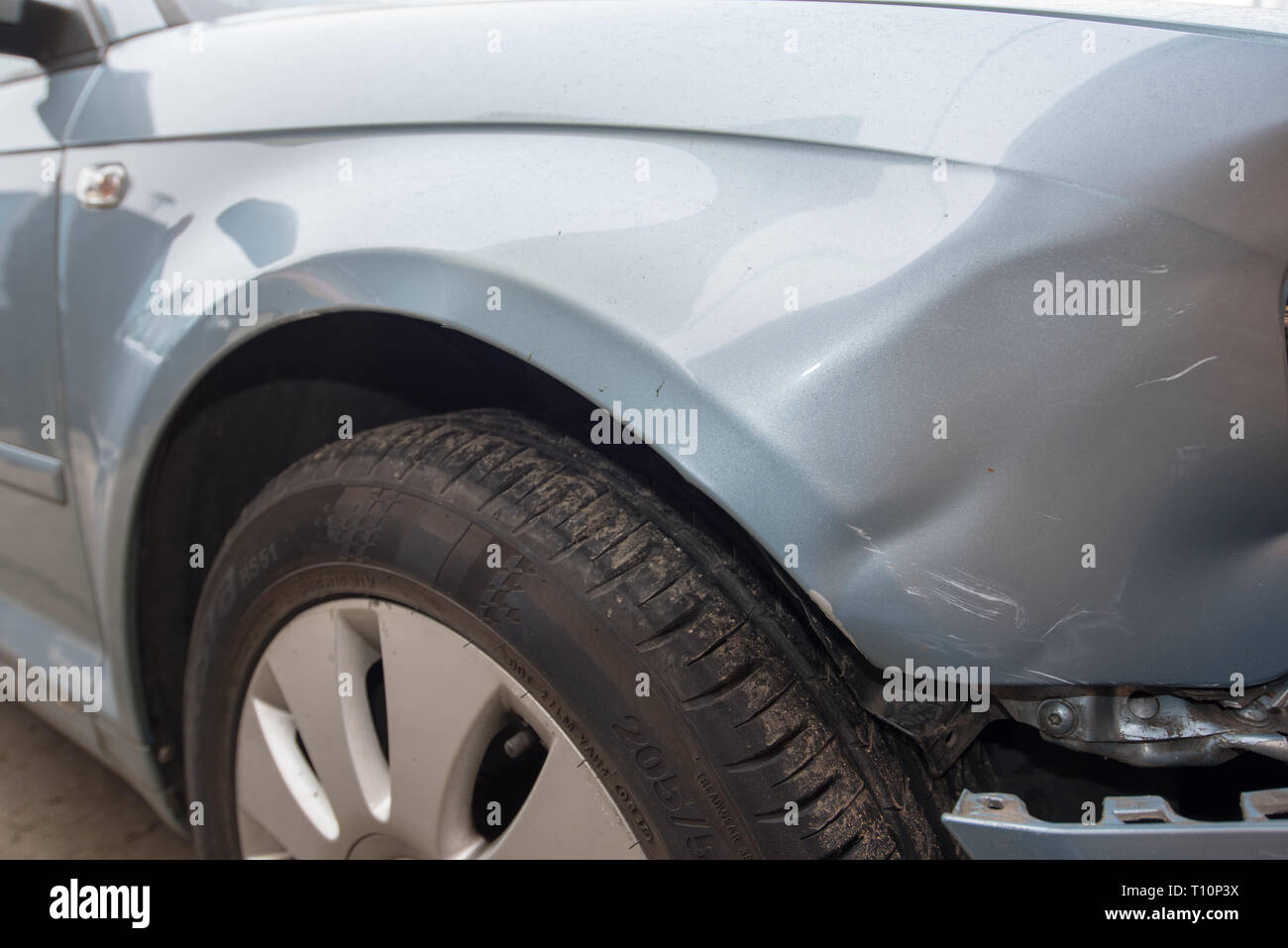 Car crash. Silver vehicle in front end collision. Damage to bumper/ wheel arch/ headlight. Brick work backgroun. UK Stock Photo