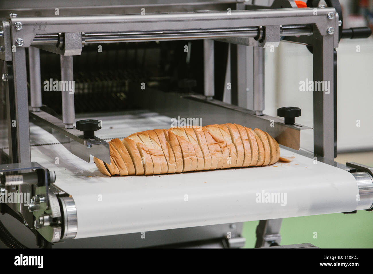 sliced white bread in cutting machine, baking equipment selective focus. Stock Photo