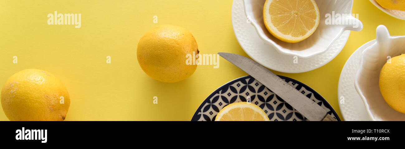 Fresh raw lemons and porcelain  tablewares on fresh yellow background. Still life, background, fresh food design Stock Photo