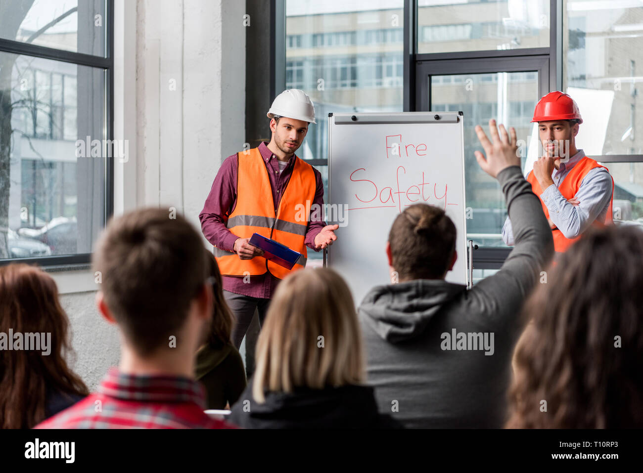 selective focus of handsome firemen in helmets giving talk on briefing