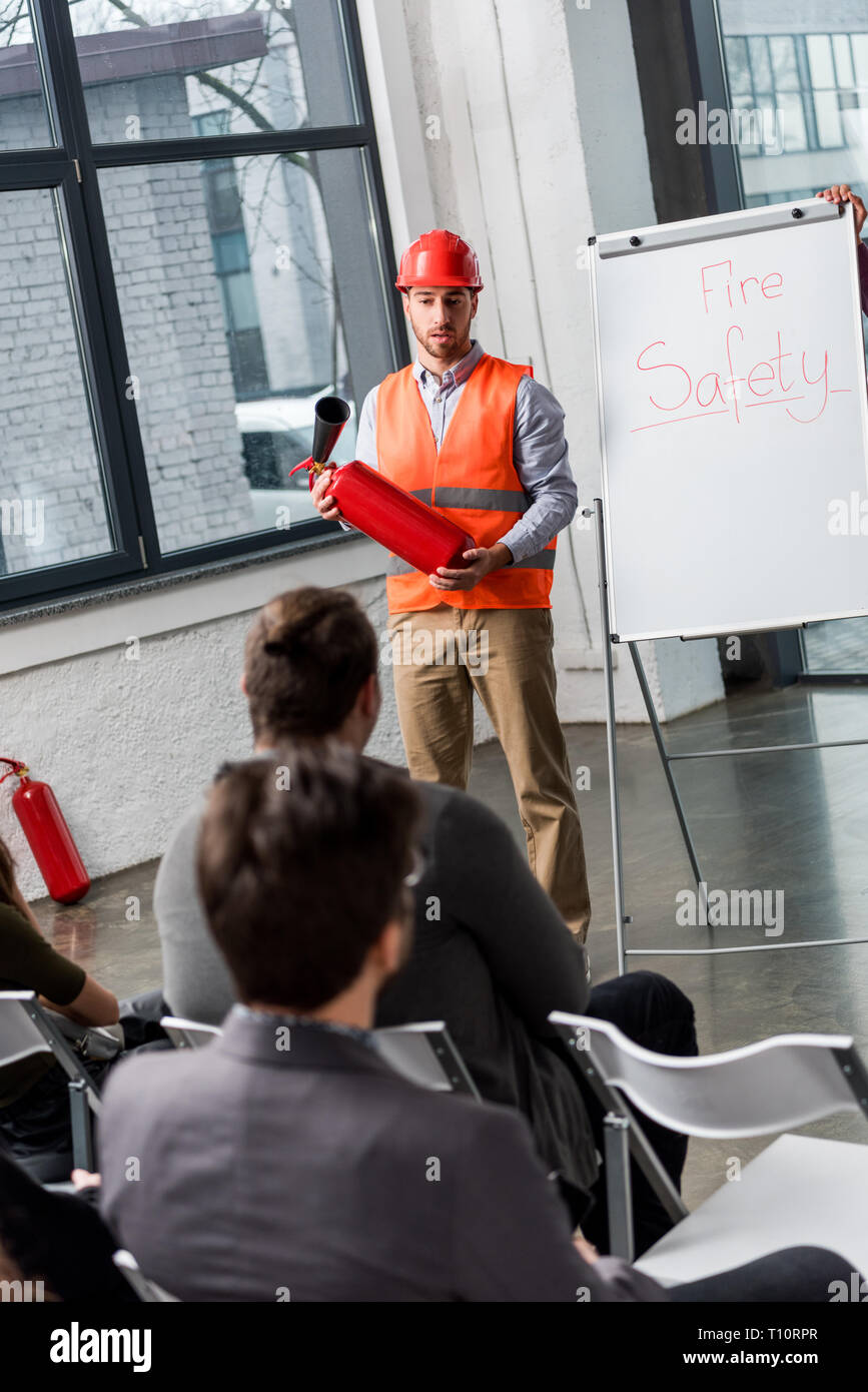 handsome fireman in helmet giving talk on briefing while holding