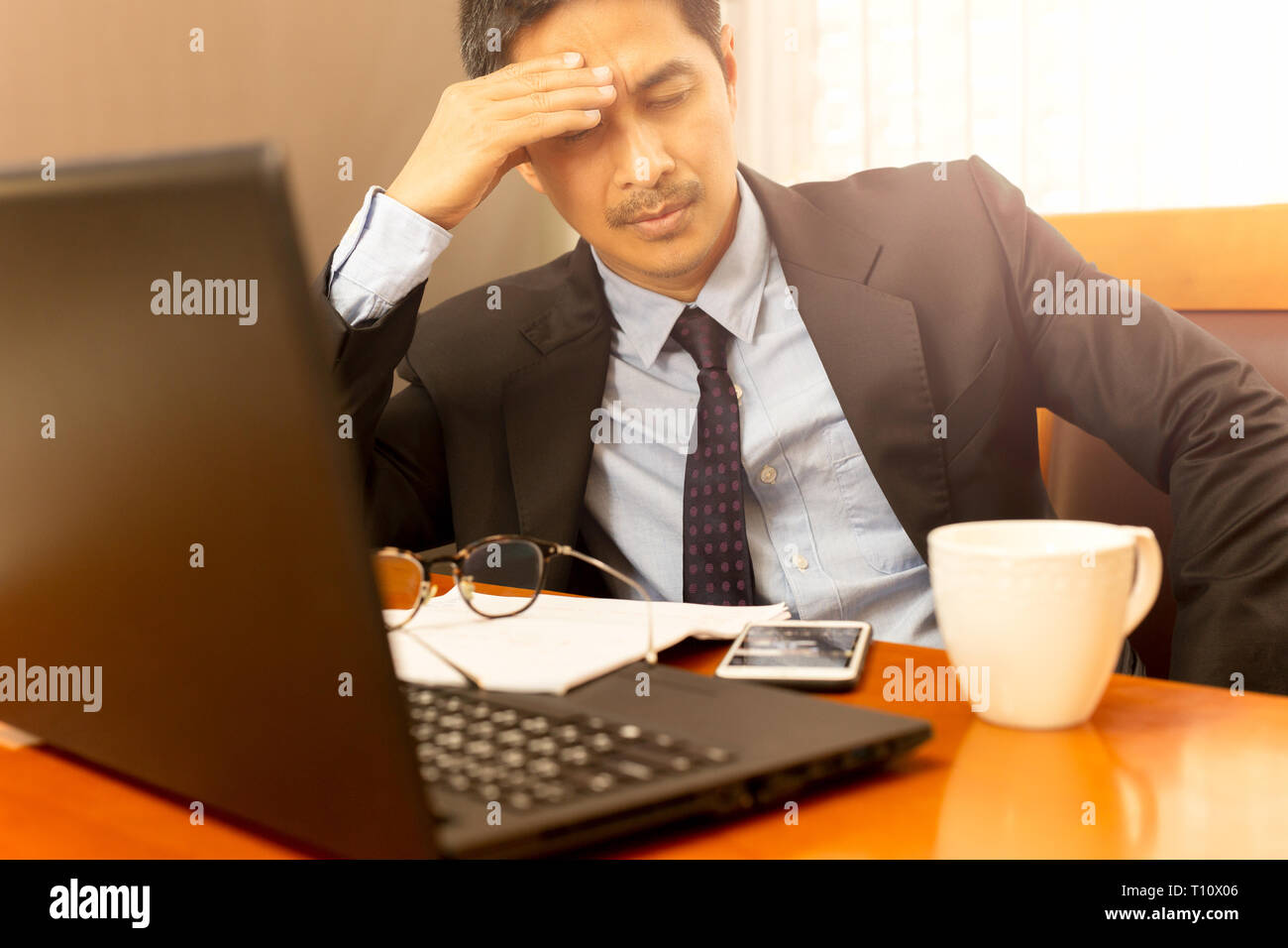 Businessman leaning with hand on his head on eyes closed feeling sleepy. Stock Photo