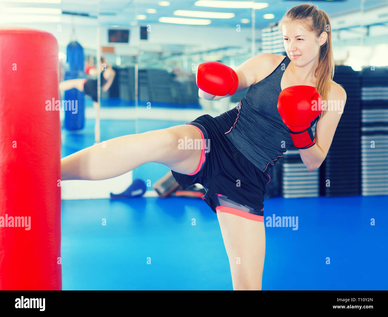Positive female is doing foot-kick in box gym Stock Photo - Alamy