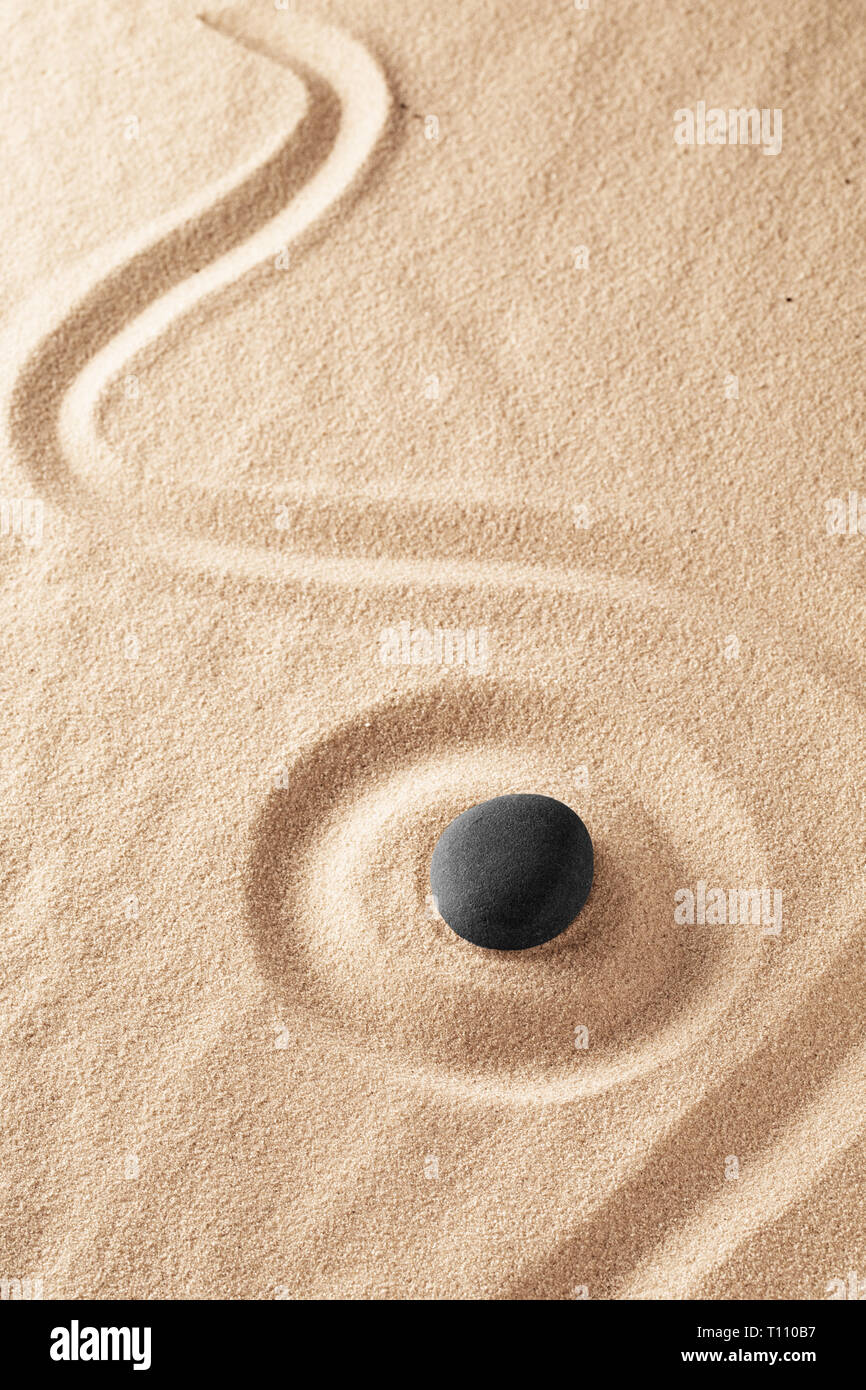 Raked sand and spa wellness healing stone. Zen buddhism meditation stone for concentration and relaxation through minimalism and purity. Spiritual bac Stock Photo