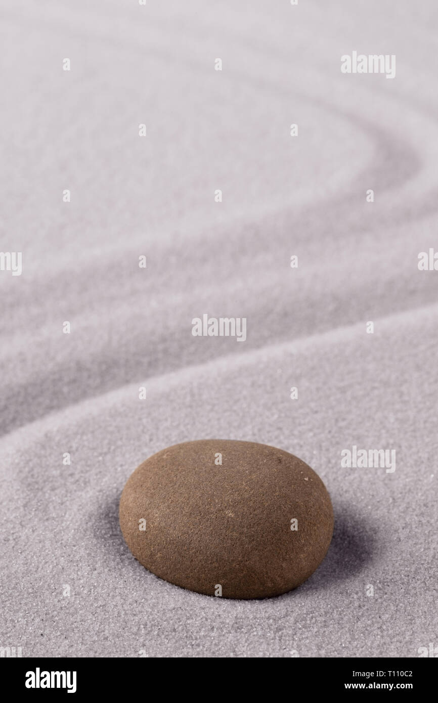 Zen meditation stone to focus and concentrate for a quit peace of mind. Spiritual raked sand background texture. Concept for harmony purity and spirit Stock Photo