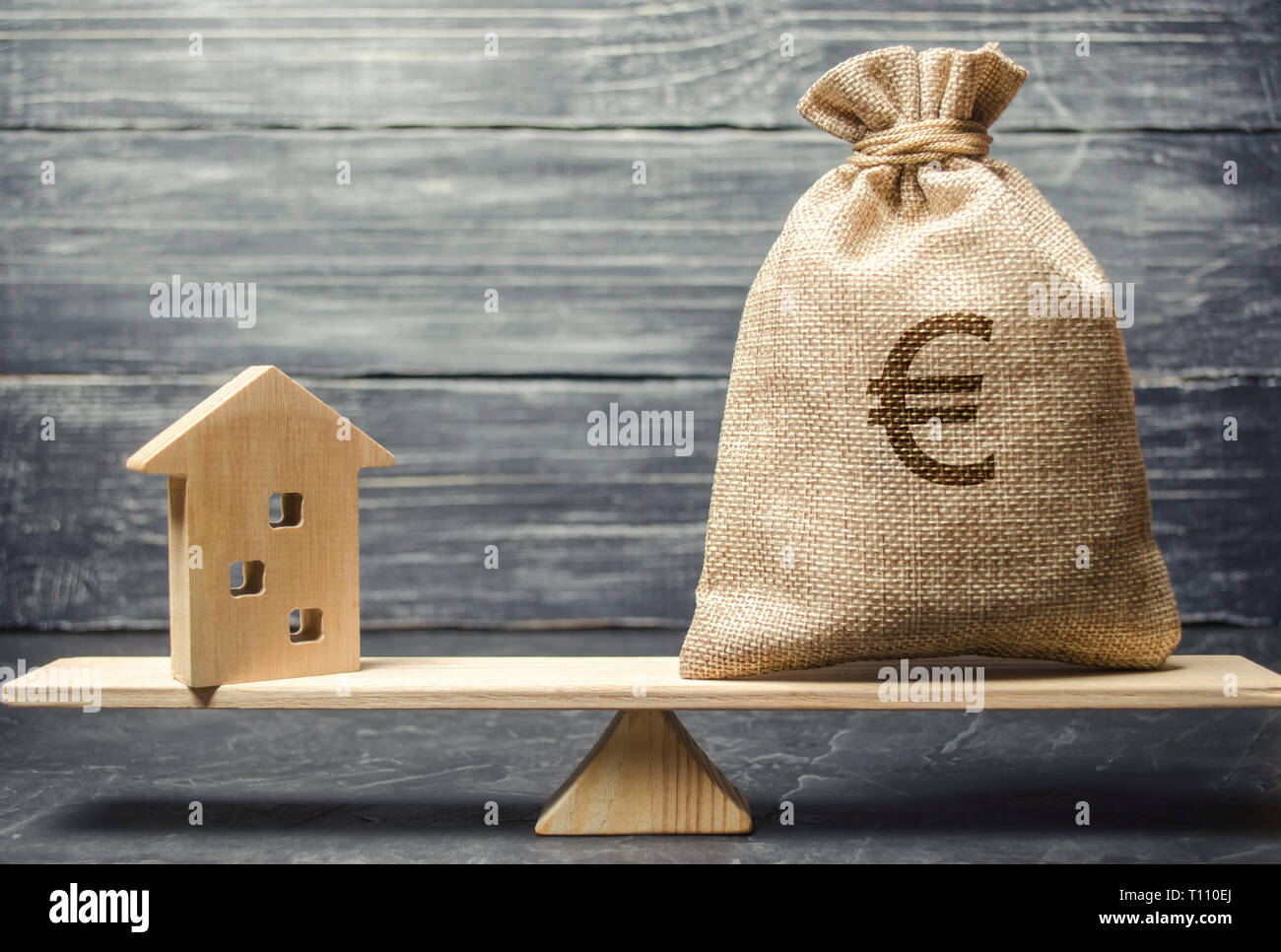A money bag and a wooden house on the scales. The concept of real