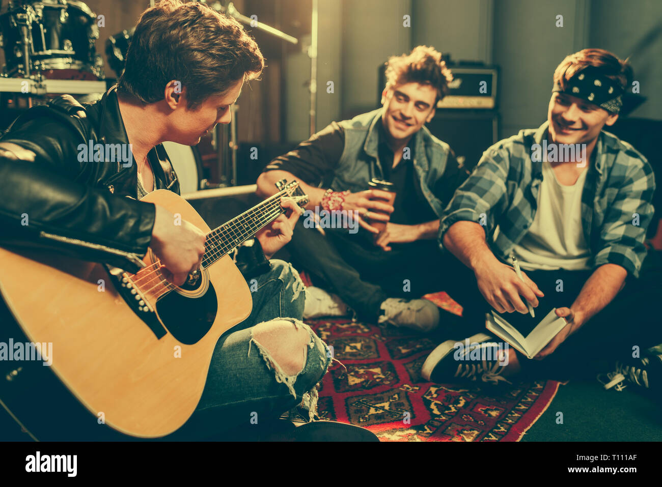 selective focus of musician playing acoustic guitar near happy friends