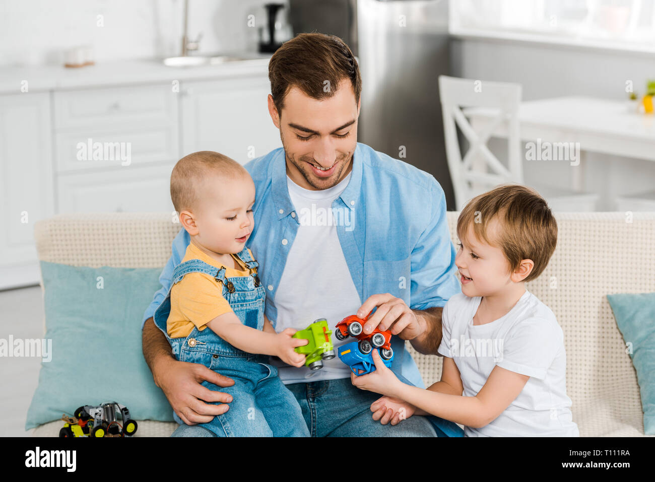 Handsome Father Sitting On Couch While Smiling Preschooler And
