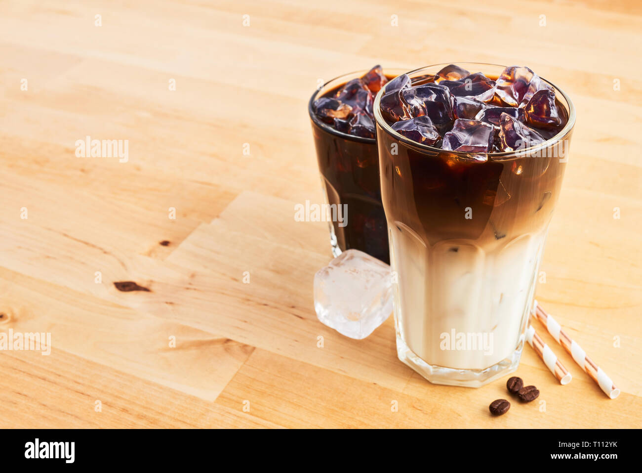 Iced coffee and latte macchiato in tall glass with straws on wooden table. Various types of coffee. Copy space for text. Stock Photo