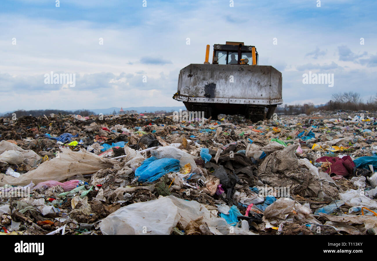 Bulldozer working on mountain of garbage in landfill Stock Photo
