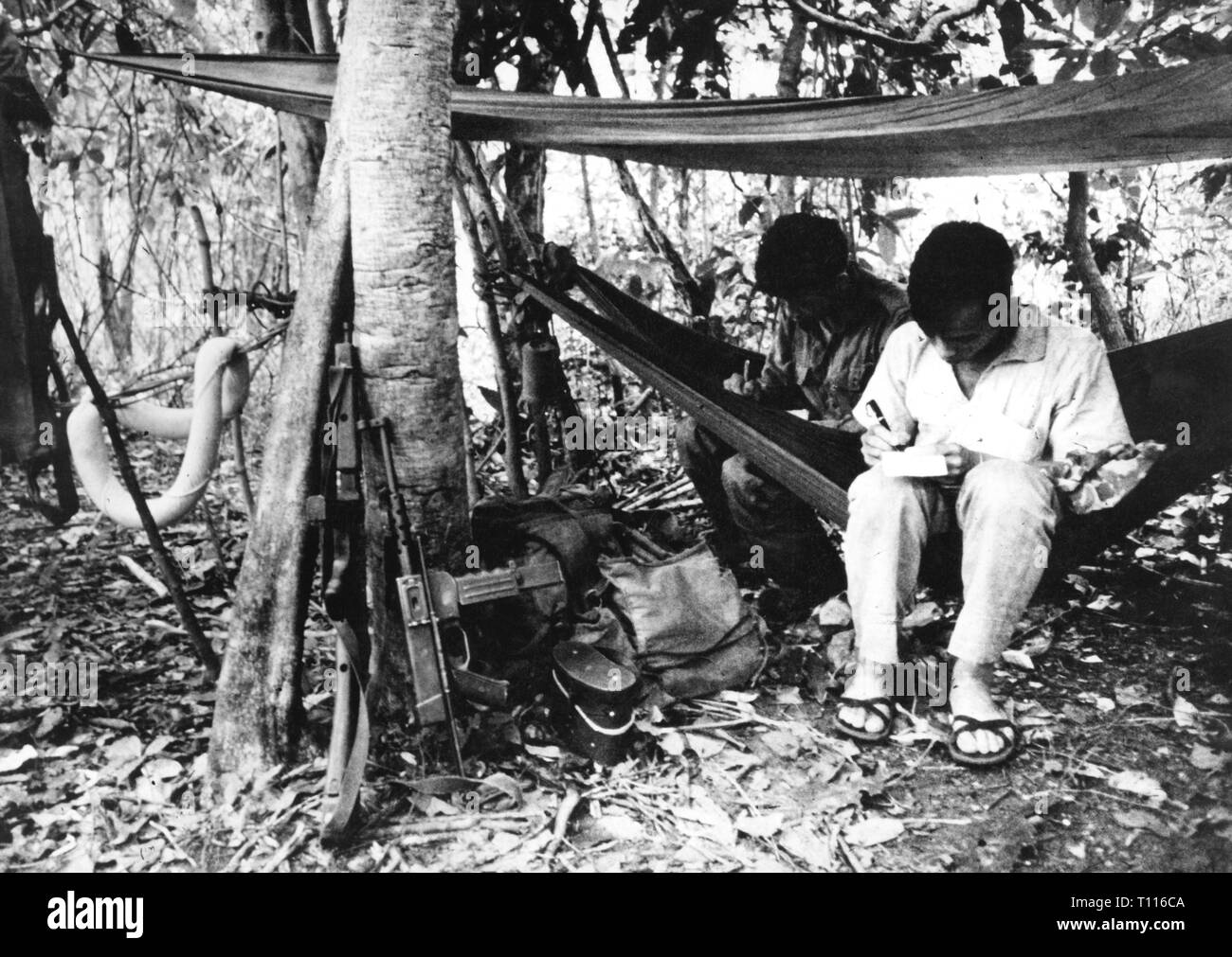 Vietnam War 1955 - 1975, Vietcong, two Vietcong fighters are writing letters, camp in the jungle, South Vietnam, 1965, writing, hammock, hammocks, fighter, people, men, man, weapons, arms, weapon, arm, armament, sub-machine gun, sub-machine guns, grease gun, Thompson, MAT 49, guerilla, guerrilla, guerillas, guerrillas, hiding-place, Viet Nam, Vietnam, war, wars, 20th century, 1960s, letter, letters, camp, camps, historic, historical, Additional-Rights-Clearance-Info-Not-Available Stock Photo