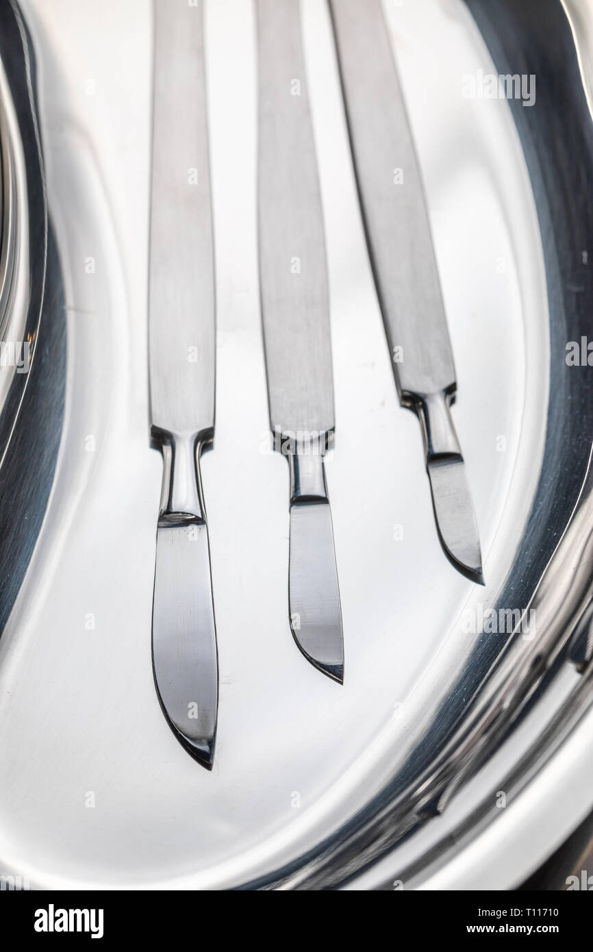 Sharp surgical scalpels on stainless steel table with blood Stock Photo