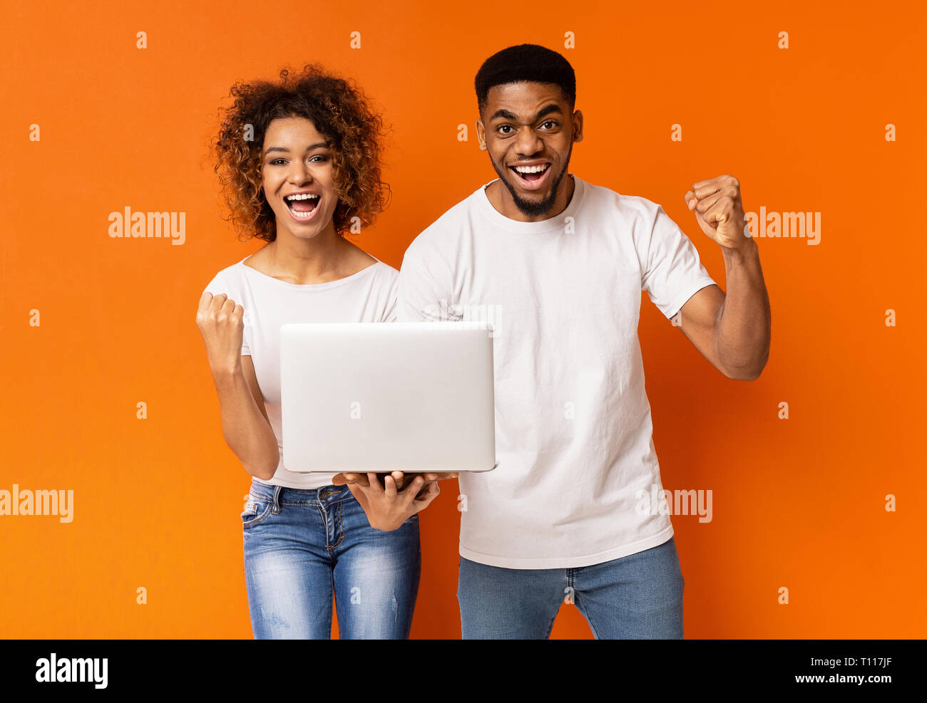 Excited black couple celebrating win with laptop Stock Photo